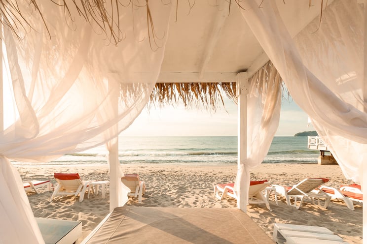 Canopy Bed with White Drapes on an Empty Beach